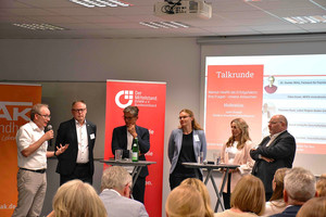 Ein Panel von fünf Personen diskutiert auf einer Bühne vor einem Publikum.