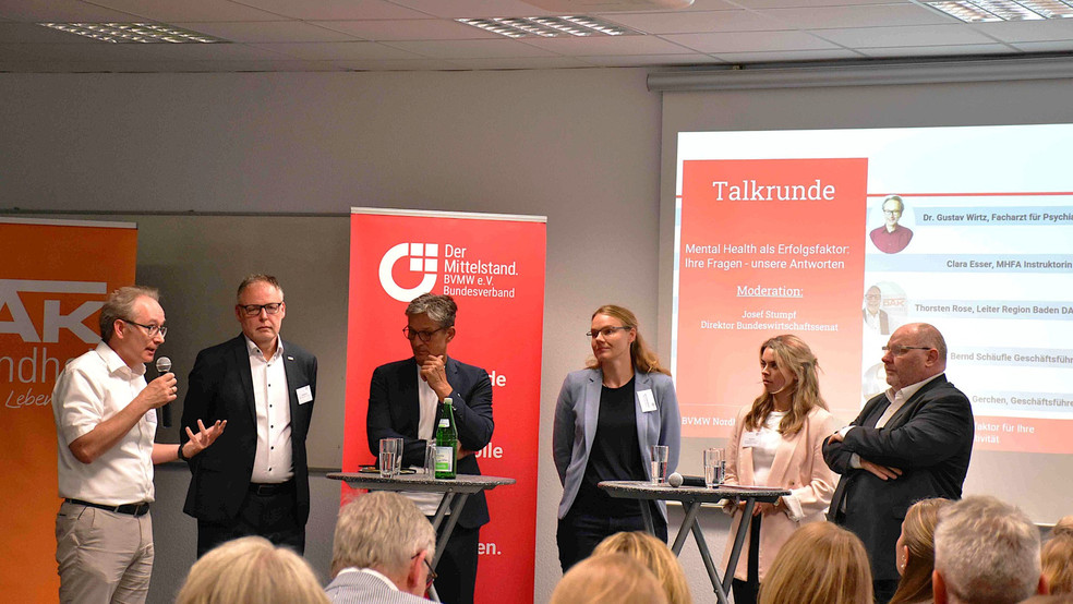 Ein Panel von fünf Personen diskutiert auf einer Bühne vor einem Publikum.