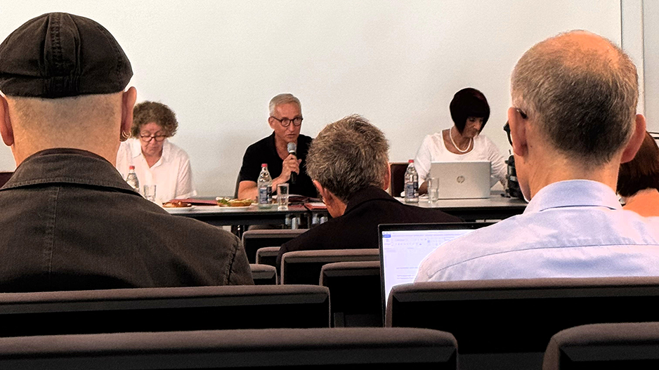 Ein Mann spricht in einem Konferenzraum vor einer Gruppe von Menschen.