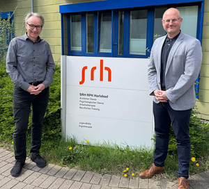v-l.n.r.: Dr. Gustav Wirtz (SRH) und Tobias Brehm (Wirtschaftsförderung Karlsbad) vor dem Gebäudeeingang der SRH RPK Karlsbad